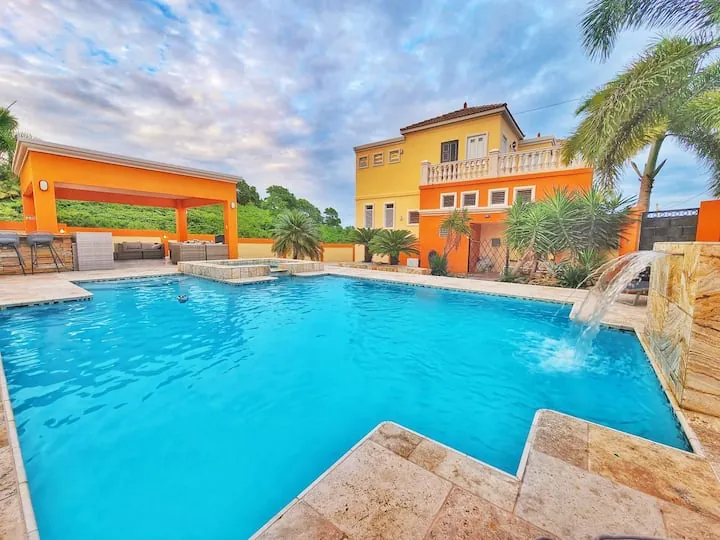 Oasis Escape House: casa amarilla y terracota con piscina y palmas